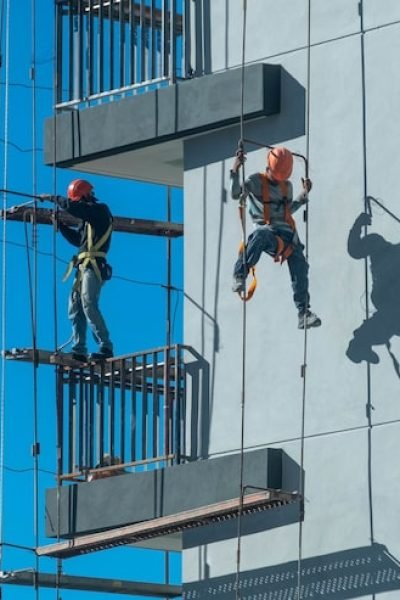 couple-workers-fixing-climbing-scaffolding-while-following-all-safety-measures_181624-46565